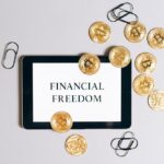 Top view of a tablet displaying 'Financial Freedom' with scattered bitcoin coins, symbolizing digital currency.